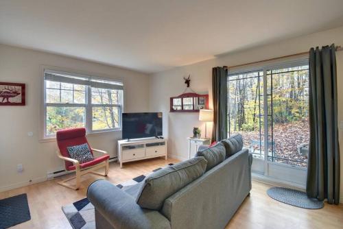 a living room with a couch and a television at Tranquility Lodge by Instant Suites in Mont-Tremblant