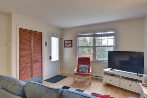 a living room with a couch and a flat screen tv at Tranquility Lodge by Instant Suites in Mont-Tremblant