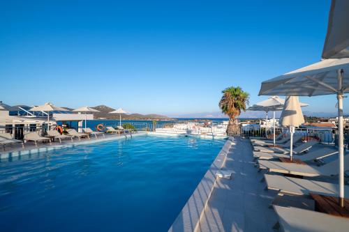 a swimming pool with lounge chairs and umbrellas at Elounda Akti Olous (Adults Only) in Elounda
