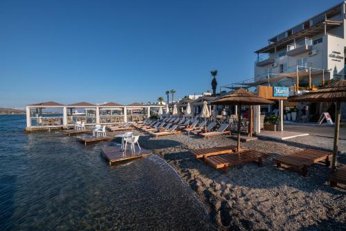 a beach with benches and umbrellas on the water at Elounda Akti Olous (Adults Only) in Elounda