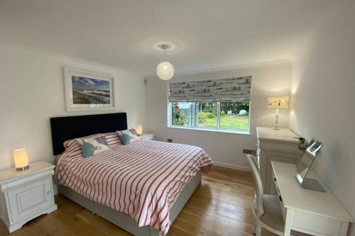 um quarto com uma cama, uma secretária e uma janela em Barton on Sea self contained, stunning sea views em Barton on Sea