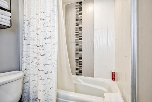 a white bathroom with a toilet and a bath tub at Luxury Studio Getaway at Blue Mountains 80114 in Blue Mountains