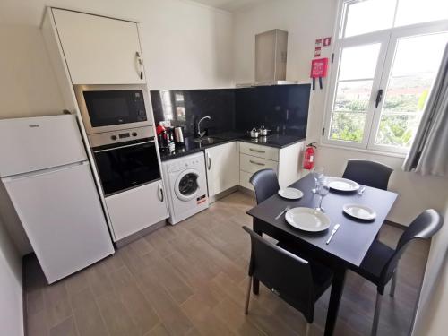 a kitchen with a table and a white refrigerator at CASA DOS AVÓS Apartments with Pool in Funchal in Funchal