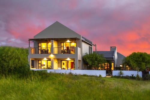 a house sitting on top of a hill with a sunset at Le Mahi Guest House in Langebaan