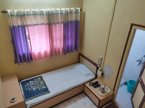 a small room with a small bed and a window at Hotel Ayodhya in Chiplun