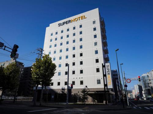 ein weißes Gebäude mit einem Schild an der Seite in der Unterkunft Super Hotel Sapporo Kitagojo Dori in Sapporo