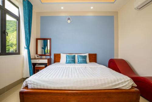 a bedroom with a large bed with blue pillows at Garden House Côn Đảo in Con Dao