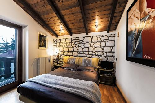a bedroom with a bed with a stone wall at Chalet Mirastelle in Pretoro