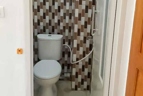 uma casa de banho com um WC e uma parede castanha e branca em RedDoorz Plus near Universitas Saburai Lampung em Lampung
