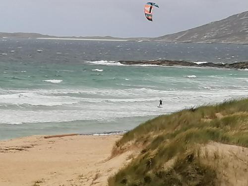 a person flying a kite over the ocean at The Fisherman's Snug self catering North Uist in Paible