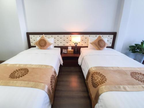a hotel room with two beds and a lamp at REIWA INN APARTMENT in Hanoi