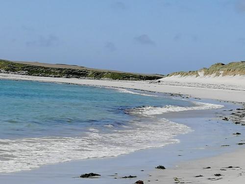 a beach with blue water and sand and hills at The Fisherman's Snug self catering North Uist in Paible