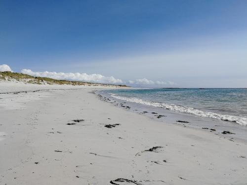 a beach with footprints in the sand and the ocean at The Fisherman's Snug self catering North Uist in Paible