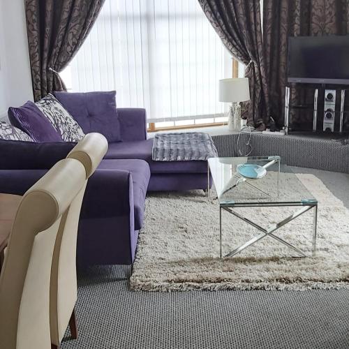 a living room with a purple couch and a glass table at Hooton Apartment 1 bed in Kilnhurst