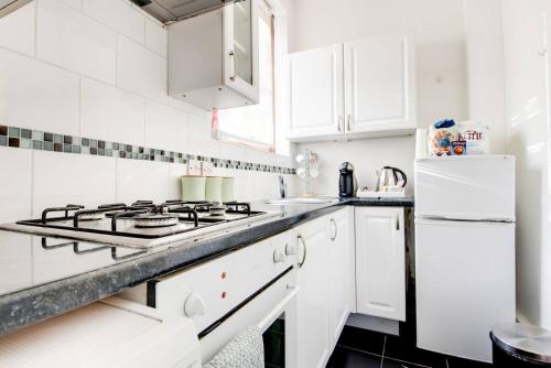 cocina blanca con fogones y nevera en Hooton Apartment 1 bed, en Kilnhurst