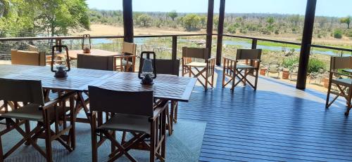 a wooden deck with tables and chairs on a balcony at Kruger Private Lodge in Marloth Park