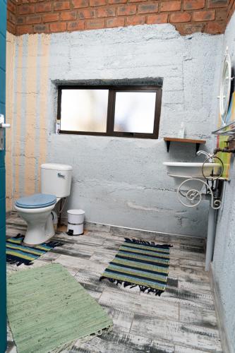 a bathroom with a toilet and a window and rugs at Otavi Vineyards Self-Catering & Camping in Otavi