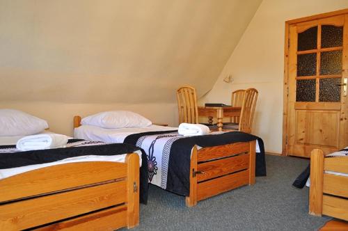 two beds in a room with two chairs and a table at Willa Orla in Zakopane