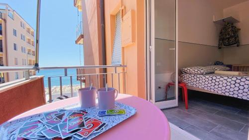 balkon z różowym stołem i łóżkiem w obiekcie Babyaccommodation Family Panoramic II w mieście Pietra Ligure