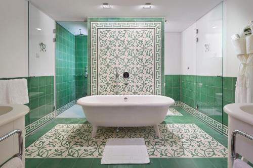 a bathroom with a tub and a green wall at Post Lech Arlberg in Lech am Arlberg