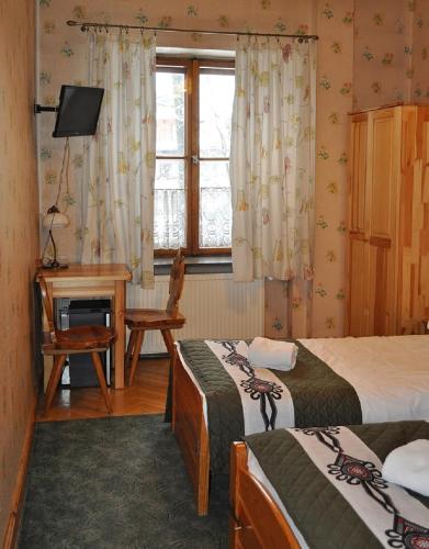 a room with two beds and a desk and a window at Willa Orla in Zakopane