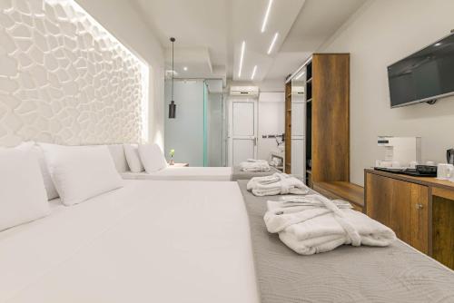 a white bedroom with two beds and a flat screen tv at Litore Luxury Living in Laganas