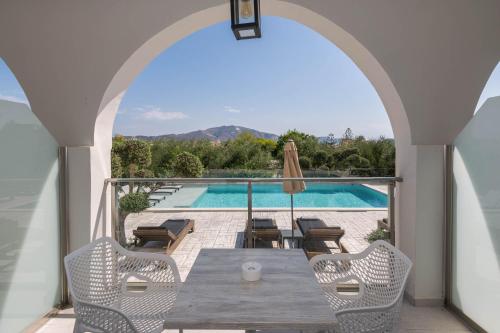 a patio with a table and chairs and a swimming pool at Litore Luxury Living in Laganas