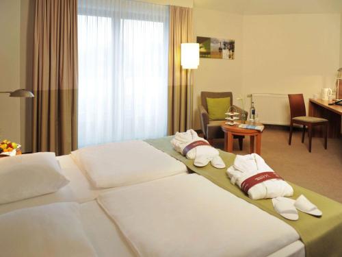 a hotel room with a bed with towels on it at Mercure Tagungs- & Landhotel Krefeld in Krefeld