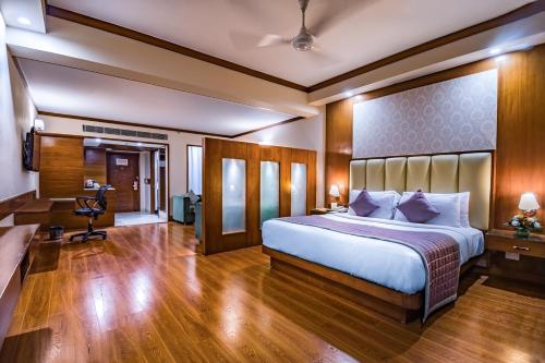 a bedroom with a large bed and a desk at Hotel Madhuban in Dehradun