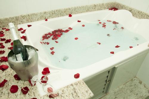 a bath tub covered in roses with a bottle of champagne at Alves Hotel in Marília