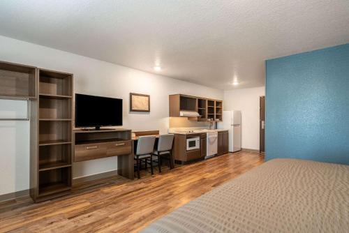 a bedroom with a bed and a desk with a television at WoodSpring Suites Sanford North I-4 Orlando Area in Sanford