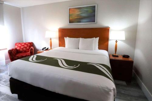 a hotel room with a large bed and a red chair at Quality Inn Miami Airport - Doral in Miami