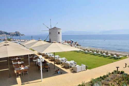 a beach with tables and umbrellas and a windmill at Bella Veranda in Anemómylos