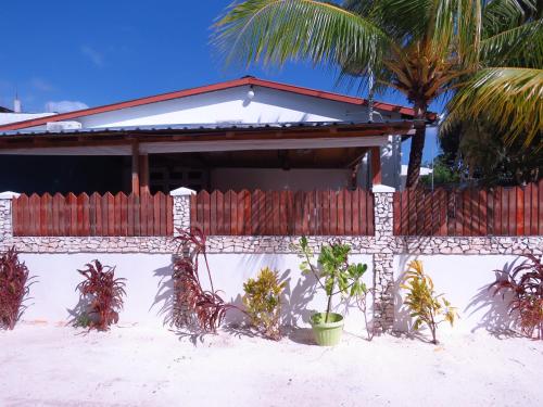 a fence in front of a house with palm trees at The Sunrise Huraa in Huraa