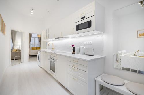 a white kitchen with white cabinets and a sink at BpR LYNX Home with A/C in Budapest