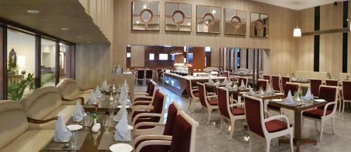 a dining room with tables and chairs in a restaurant at Hotel Madhuban in Dehradun