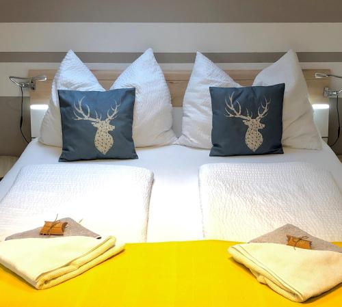 ein Bett mit zwei Kissen und zwei Handtüchern darauf in der Unterkunft FeWo Atterseeperle - 80m2 mit See- und Gebirgsblick in Steinbach am Attersee