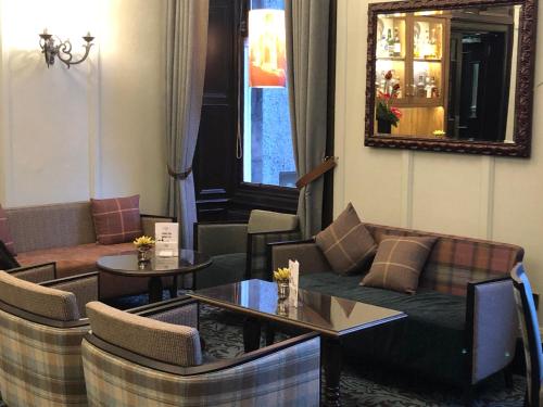 a living room with couches and tables and a mirror at The Parliament House Hotel in Edinburgh