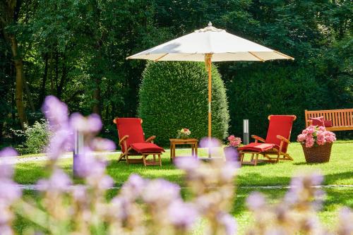 a group of chairs and a table with an umbrella at Parkhotel Rothof in Munich