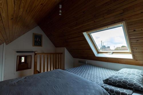 ein Schlafzimmer mit einem Bett und einem Fenster im Dachgeschoss in der Unterkunft Le nid breton in Lézardrieux