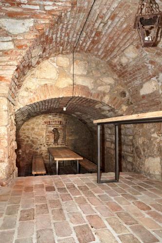 a stone room with a wooden table and a bench at Apartmán NEWSTALGIE in Mikulov
