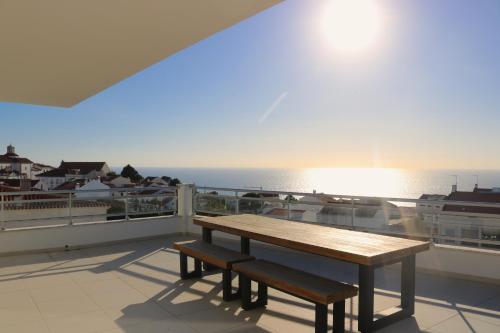 un banco de madera en un balcón con vistas al océano en Pico Do Feliz - The Penthouse & The Village By Silver Prop, en Nazaré