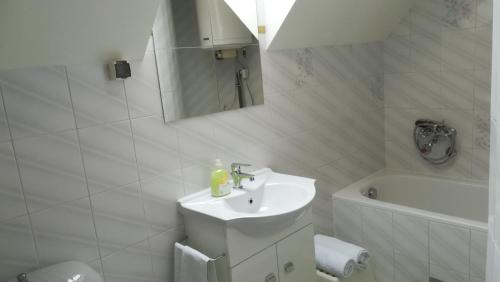 a white bathroom with a sink and a toilet and a tub at MA-JA 4 in Bük