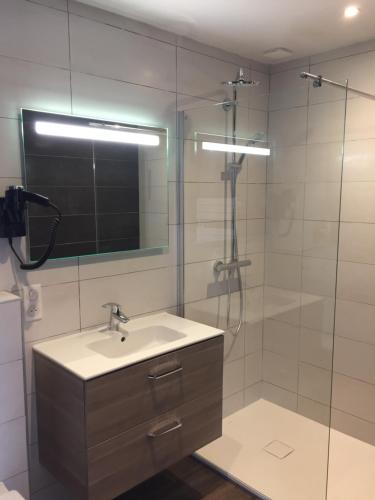 La salle de bains est pourvue d'un lavabo et d'une douche avec un miroir. dans l'établissement nuit sur le pont 5, à Landerneau