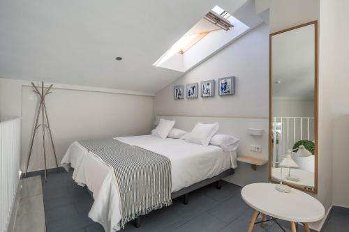 a white bedroom with a bed and a chair at Mon Suites Carmen in Valencia