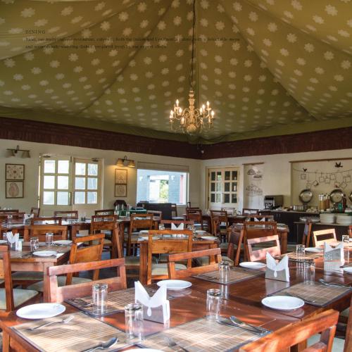 a dining room with tables and chairs and a chandelier at Vanaashrya Resort and Spa Sariska in Tehla