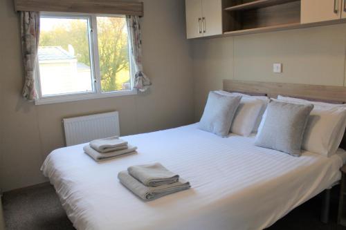 een slaapkamer met een wit bed en handdoeken bij Newquay Bay Resort - Spacious - Sleeps 6 - Close to Porth Beach in Newquay