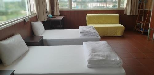 a room with two beds and a yellow chair at Mingyuan Homestay in Jinhu