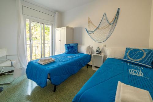 サン・フェリウ・デ・ギホルスにあるApartamentos Costa Brava Las Vistasのベッドルーム1室(青いシーツと窓付きのベッド2台付)