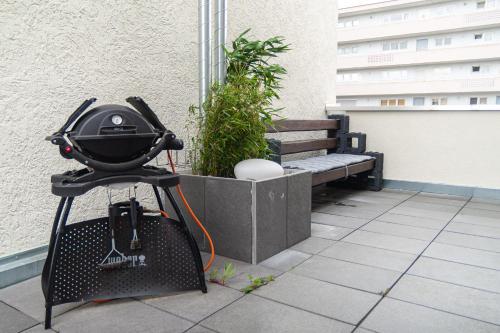 a grill on a stand on a balcony with a bench at soulfactory budget in Neu Ulm